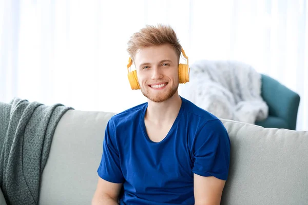 Knappe jongeman die thuis naar muziek luistert — Stockfoto