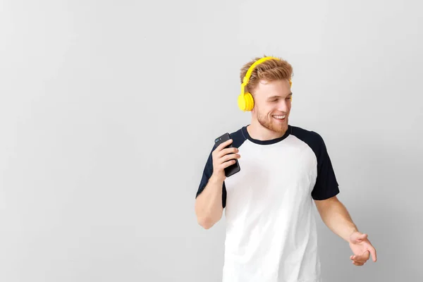 Knappe jongeman luisteren naar muziek op lichte achtergrond — Stockfoto