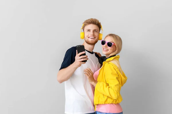 Pareja joven escuchando música sobre fondo claro — Foto de Stock