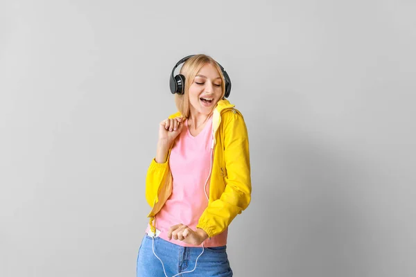 Beautiful young woman listening to music on light background — Stock Photo, Image