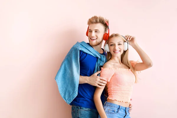 Pareja joven escuchando música sobre fondo de color — Foto de Stock