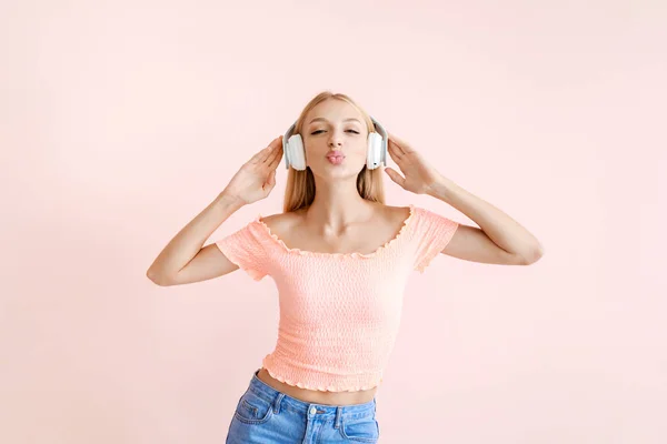 Mooie jonge vrouw luisteren naar muziek op kleur achtergrond — Stockfoto