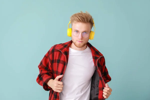 Handsome young man listening to music on color background — Stock Photo, Image