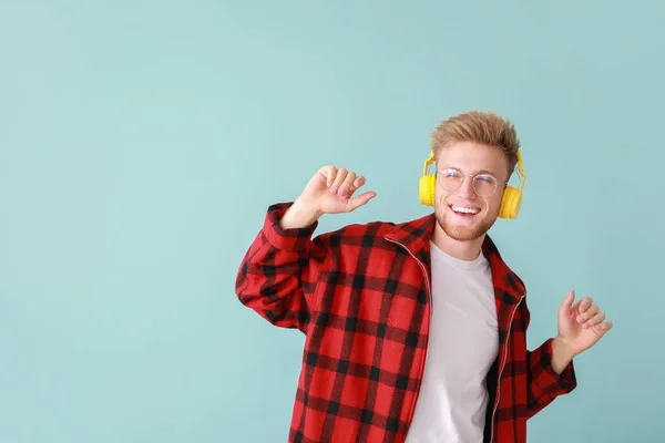 Handsome young man listening to music on color background — Stock Photo, Image