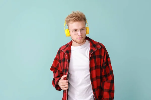 Knappe jongeman luisteren naar muziek op kleur achtergrond — Stockfoto