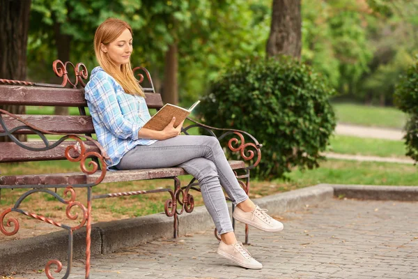 Woman reading book while relaxing in park — Stock Photo, Image