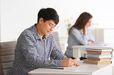 Sınıfta masada oturan Asyalı öğrenci