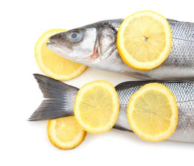 Beyaz arka planda biberiye ve limon ile taze levrek balık