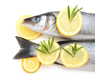 Beyaz arka planda biberiye ve limon ile taze levrek balık