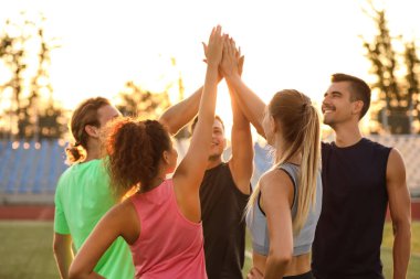 Stadyumda el ele tutuşan sportif gençler grubu