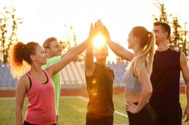 Stadyumda el ele tutuşan sportif gençler grubu