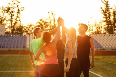 Stadyumda el ele tutuşan sportif gençler grubu
