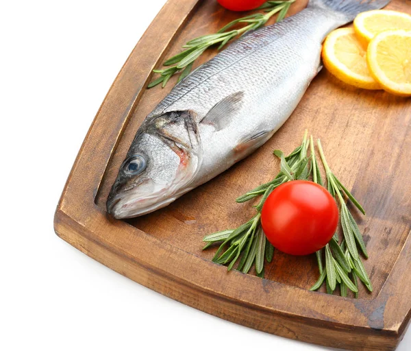 Board with fresh seabass fish, lemon, rosemary and tomato on white background — Stock Photo, Image