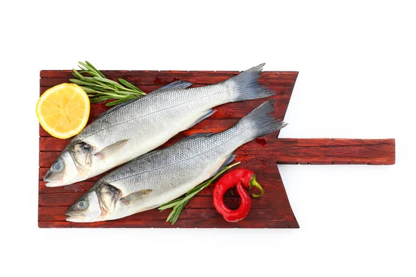 Board with fresh seabass fish, rosemary, chili pepper and lemon on white background — Stock Photo, Image