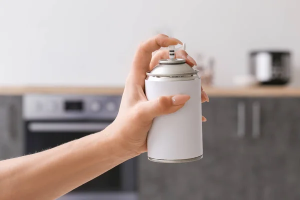 Woman spraying air freshener in kitchen — Stock Photo, Image