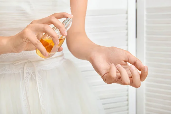 Beautiful young bride with bottle of perfume at home, closeup — Stock Photo, Image