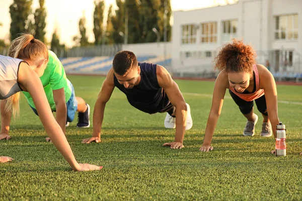 Grupa sportowych szkoleń dla młodych ludzi na stadionie — Zdjęcie stockowe