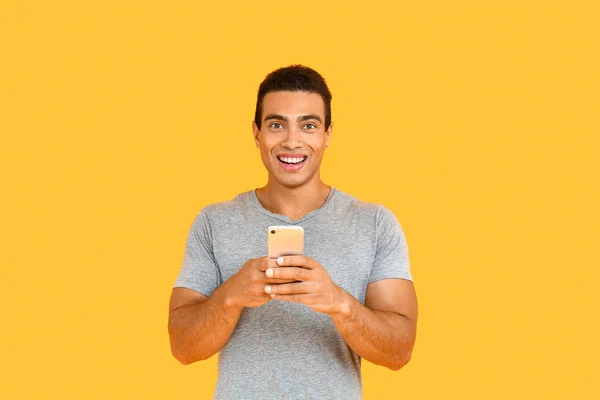 Hombre afroamericano guapo con teléfono móvil sobre fondo de color — Foto de Stock