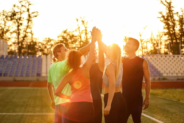 Group of sporty young people putting hands together at the stadium — Stock Photo, Image