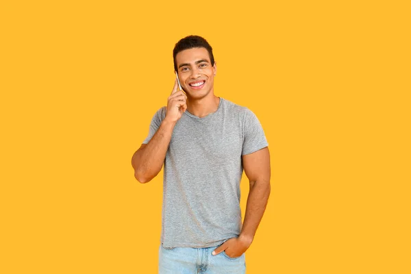 Hombre afroamericano guapo hablando por teléfono sobre fondo de color — Foto de Stock