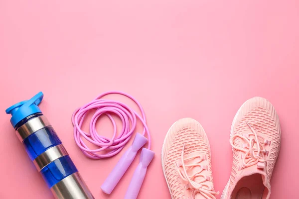 Sport-Wasserflasche, Schuhe und Springseil auf farbigem Hintergrund — Stockfoto
