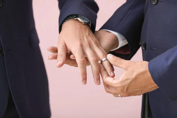 Heureux gay couple échange anneaux sur leur mariage jour sur couleur fond Gros plan — Photo