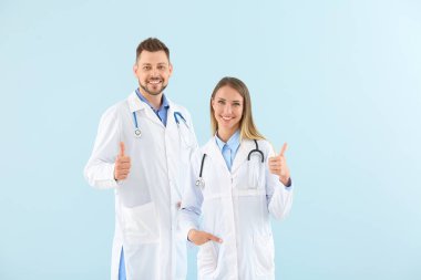 Erkek ve kadın doktorlar açık renk arka plan üzerinde thumb-up gösteren