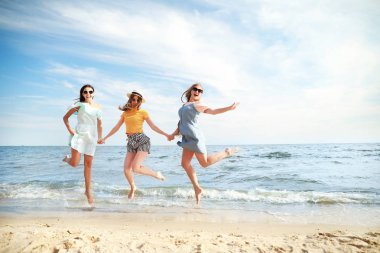 Tatil beldesinde deniz plajında mutlu atlama genç kadınlar