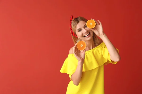 Happy beautiful woman with orange fruit on color background — Stock Photo, Image