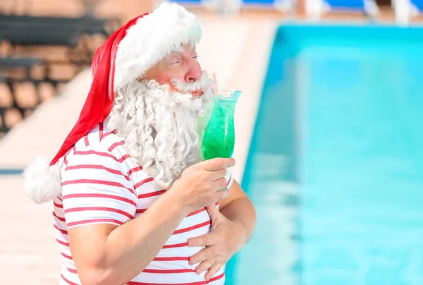 Santa Claus with cocktail near swimming pool at resort — Stock Photo, Image