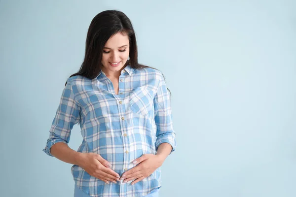 Fiatal terhes nő színes háttér — Stock Fotó