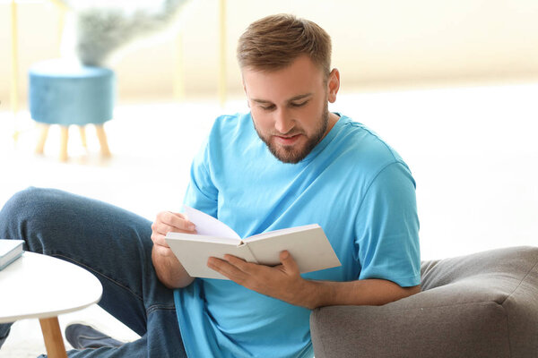 Красивый молодой человек читает книгу дома