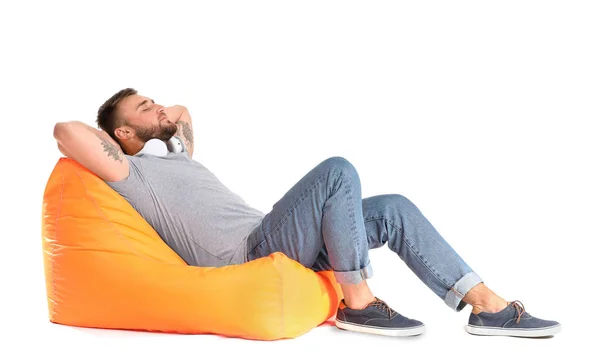 Bello giovane uomo rilassante su beanbag contro sfondo bianco — Foto Stock