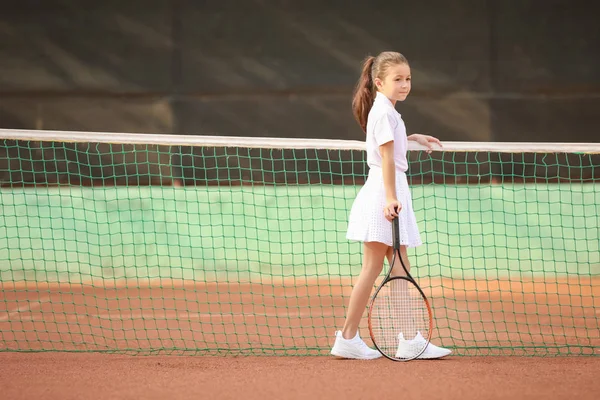 Маленькая девочка играет в теннис на корте — стоковое фото