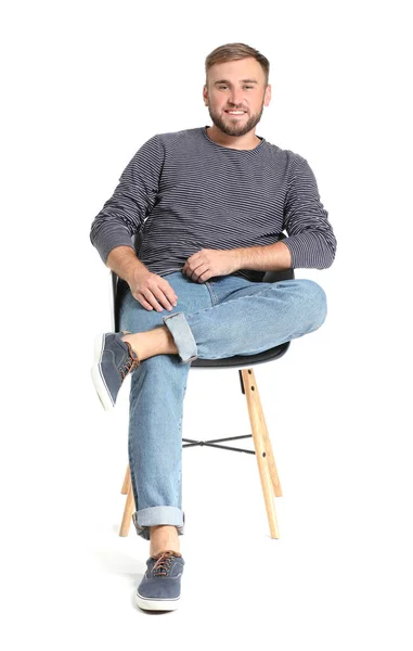 Handsome young man sitting on chair against white background — Stock Photo, Image