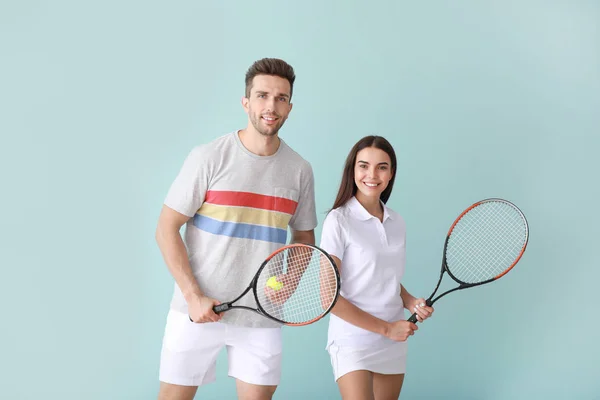 Jong stel met tennisrackets op kleur achtergrond — Stockfoto
