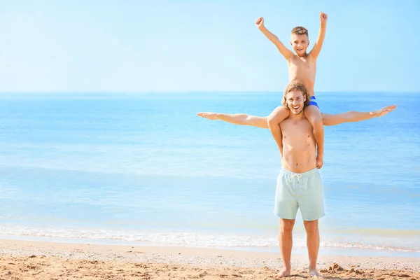 Hombre feliz con su pequeño hijo descansando en la playa del mar — Foto de Stock