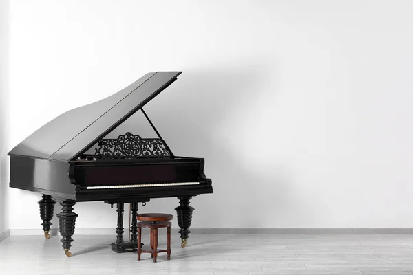 Black grand piano near white wall in empty room — Stock Photo, Image