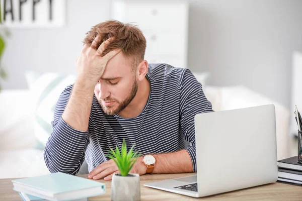 Stressed young man at table in office — Stock Photo, Image