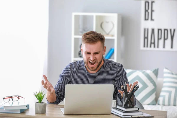 Stressed young man at table in office — Stock Photo, Image