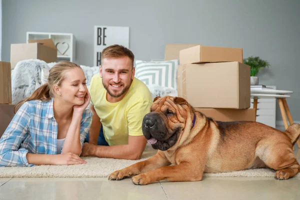 Happy couple with cute dog after moving into new house — Stock Photo, Image