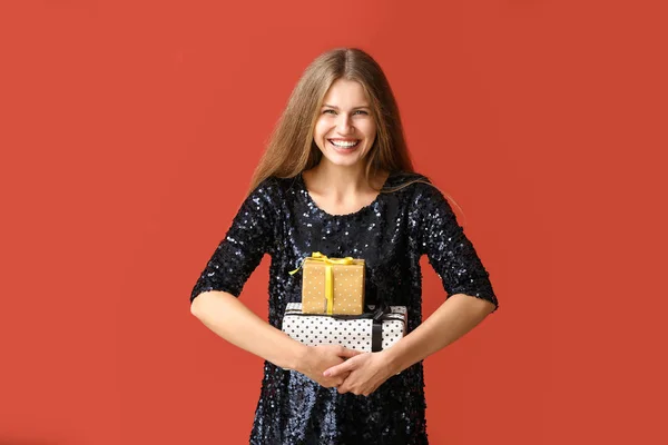 Beautiful young woman with gifts on color background — Stock Photo, Image
