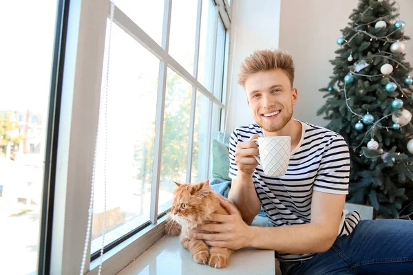 Young man with cute cat at home on Christmas eve — Stock Photo, Image