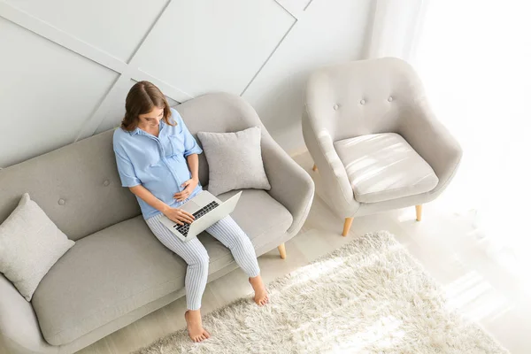Gyönyörű terhes nő laptop ül a kanapén otthon — Stock Fotó