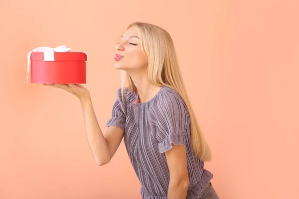 Belle jeune femme avec cadeau sur fond de couleur — Photo