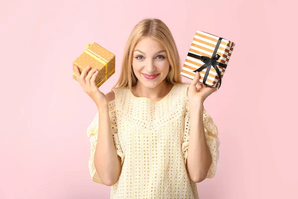 Beautiful young woman with gifts on color background — Stock Photo, Image