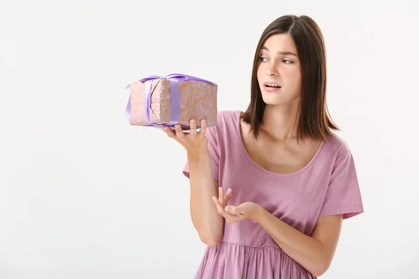 Displeased young woman with gift on white background