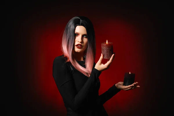 Beautiful woman with candles dressed for Halloween on dark background