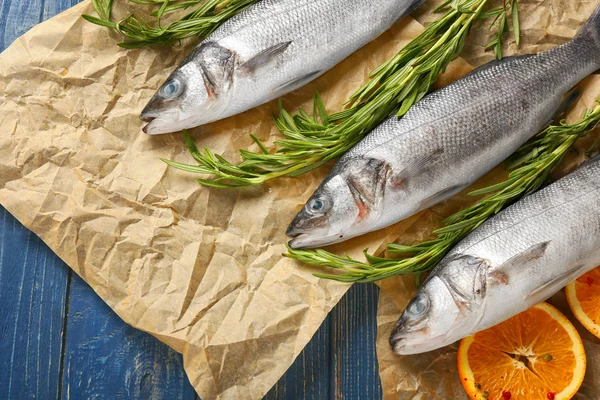 Ikan laut segar dengan oranye dan rosemary pada latar belakang kayu — Stok Foto