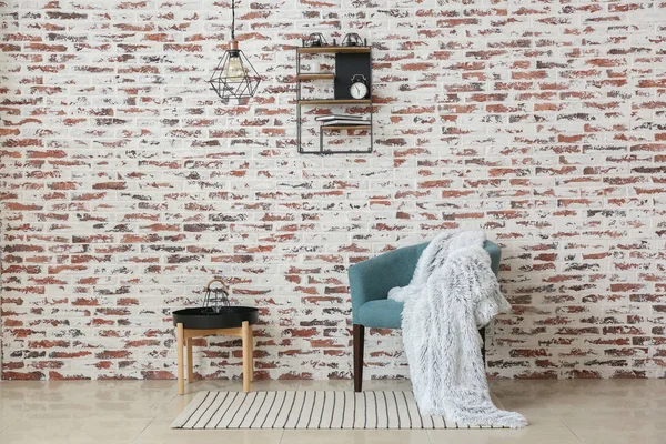 Comfortable armchair and table near brick wall — Stock Photo, Image